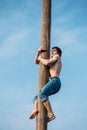 Young man climbs on a wooden post on traditional holiday dedicated to the approach of spring - Slavic celebration