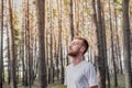 Young man with closed eyes enjoying the nature during a walk or jogging in the forest.