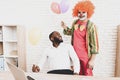 Young Man in Clown Costume with Baloons in Office. Royalty Free Stock Photo