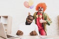 Young Man in Clown Costume with Baloons in Office. Royalty Free Stock Photo