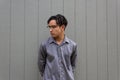 Young man in collared shirt, serious demeanor, profile view with glasses and natural black hair in dreads