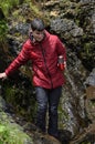 Young man collects water in a thermos of a waterfall