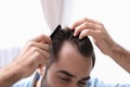 Young man with comb indoors. Hair loss problem Royalty Free Stock Photo