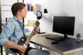 Young man with computer playing guitar at home Royalty Free Stock Photo