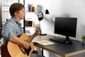 Young man with computer playing guitar at home Royalty Free Stock Photo