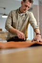 young man concentrated on scratching, or marking leather.