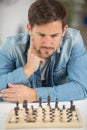 Young man considering next chess move