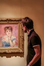 A young man considering the picture of Renoir `Portrait of the Actress Jeanne Samary` in the art gallery of the Pushkin Museum.