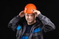 A young man construction worker in a safety helmet and work uniform on a black background Royalty Free Stock Photo