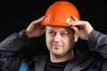 A young man construction worker in a safety helmet and work uniform on a black background Royalty Free Stock Photo