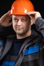 A young man construction worker in a safety helmet and work uniform on a black background Royalty Free Stock Photo