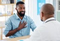 Young man in a consult with his gp. African american patient talking to doctor about chest pain. Medical professional in Royalty Free Stock Photo