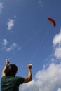Young man controlling a red kite in the blue sky Royalty Free Stock Photo