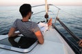 A young man controls a white sailing yacht. the captain of the sailing boat on board we meet the sunset.