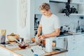 Young man cooking brownie cake on the light modern kitchen at home. Preparing steps for baking cake. Culinary hobby Royalty Free Stock Photo