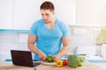 Young man cooking healthy meal vegetables computer internet eating Royalty Free Stock Photo