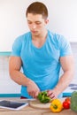 Young man cooking healthy meal vegetables tablet internet portrait format eating Royalty Free Stock Photo