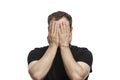 The young man covered his face with his hands. Brunette in a black T-shirt. Disturbing emotions. Isolated on white background Royalty Free Stock Photo