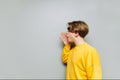 Young man cramps his palms to the side on copy space on a gray background. The guy speaks aside on an empty place on a background Royalty Free Stock Photo