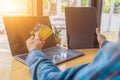 A young man with a credit card in his hand, sitting in agitation in front of a computer when he sees a debt collection document Royalty Free Stock Photo