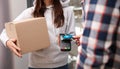 Young man with credit card using bank terminal for delivery payment at doorway