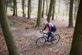 Young man cross-country cycling between trees in a forest Royalty Free Stock Photo