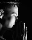 Young man in crown of thorns, martyr with closed eys imploringly clasped his hands closeup