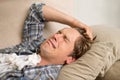 Dealing with a bad breakup. A young man crying while lying on the sofa with tissues. Royalty Free Stock Photo
