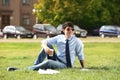 Young man with cup of coffee sitting on green lawn Royalty Free Stock Photo