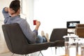 Young man with cup of drink relaxing in comfortable chair Royalty Free Stock Photo