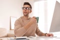 Young man with cup of drink relaxing at table in office Royalty Free Stock Photo