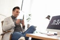 Young man with cup of drink relaxing at table in office Royalty Free Stock Photo