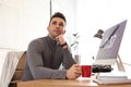 Young man with cup of drink relaxing in office during break Royalty Free Stock Photo