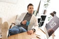 Young man with cup of drink relaxing in office during break Royalty Free Stock Photo