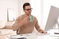 Young man with cup of drink relaxing at table in office Royalty Free Stock Photo