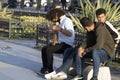 Young man with curly hair on the street is singing with a violin instrument. He sits on the bench. People give money