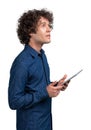 Young man with curly hairs with tablet digital device in hands, looking up, isolated over white background. Concept of business Royalty Free Stock Photo