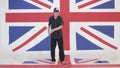 Young man with custodian helmet is imitating pointsman at studio with UK flag