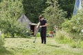 A young man cuts the grass with a trimer at his summer cottage