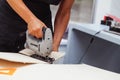 Young man cuts a pattern on plywood with an electrical fretsaw