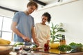 Young man cutting vegetables while woman holding pepper and watching him. Vegetarians preparing healthy meal in the Royalty Free Stock Photo