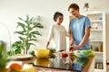 Young man cutting vegetables while woman watching him. Vegetarians preparing healthy meal in the kitchen together Royalty Free Stock Photo