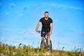 Young man cycling on a green meadow against blue sky with clouds. Royalty Free Stock Photo