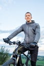 Young man cycling on a rural road through meadow