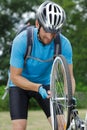 young man cyclist pumping wheel bike