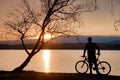 Young man cyclist silhouette on pink orange sky and sunset background on the beach. Royalty Free Stock Photo