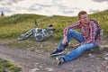 Young man cyclist sits on the edge of a dirt road