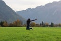 Young man dabbing mid jump in an evergreen field with beautiful mountains in the background Royalty Free Stock Photo