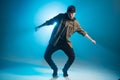 Young man dancer dancing funky hip hop on isolated studio neon blue background