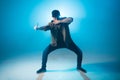 Young man dancer dancing funky hip hop on isolated studio neon blue background